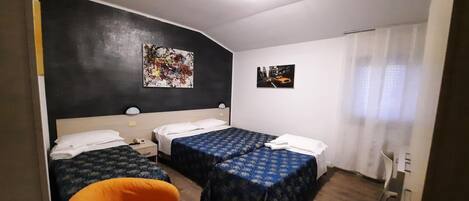 A hotel room with two beds, a chair, and artwork on the walls.