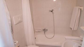 A bathroom with a toilet, bidet, bathtub, and sink.