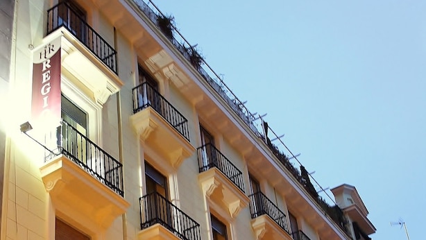 A multi-story hotel with balconies, a sign reading "Hotel Dregi," and a street lamp in the foreground. - Hostal Regio (Madrid)