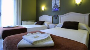 A hotel room with two beds, a nightstand, a lamp, and a painting of the Eiffel Tower. - Hostal Regio (Madrid)