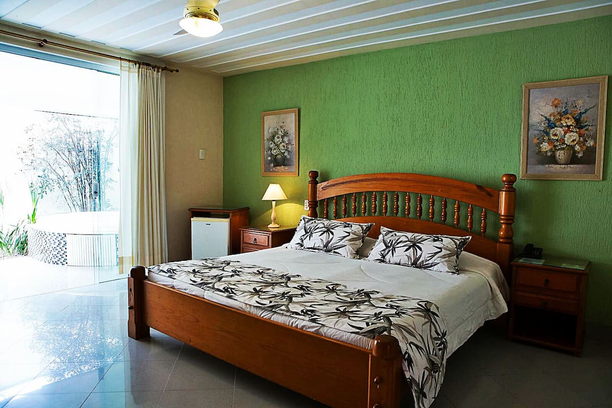 Ein Schlafzimmer mit einem hölzernen Bett, grünen Wänden und zwei Bildern.