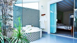 Een moderne badkamer met een wand betegeld met mozaïek, een vrijstaand bad en een zichtbare douche.