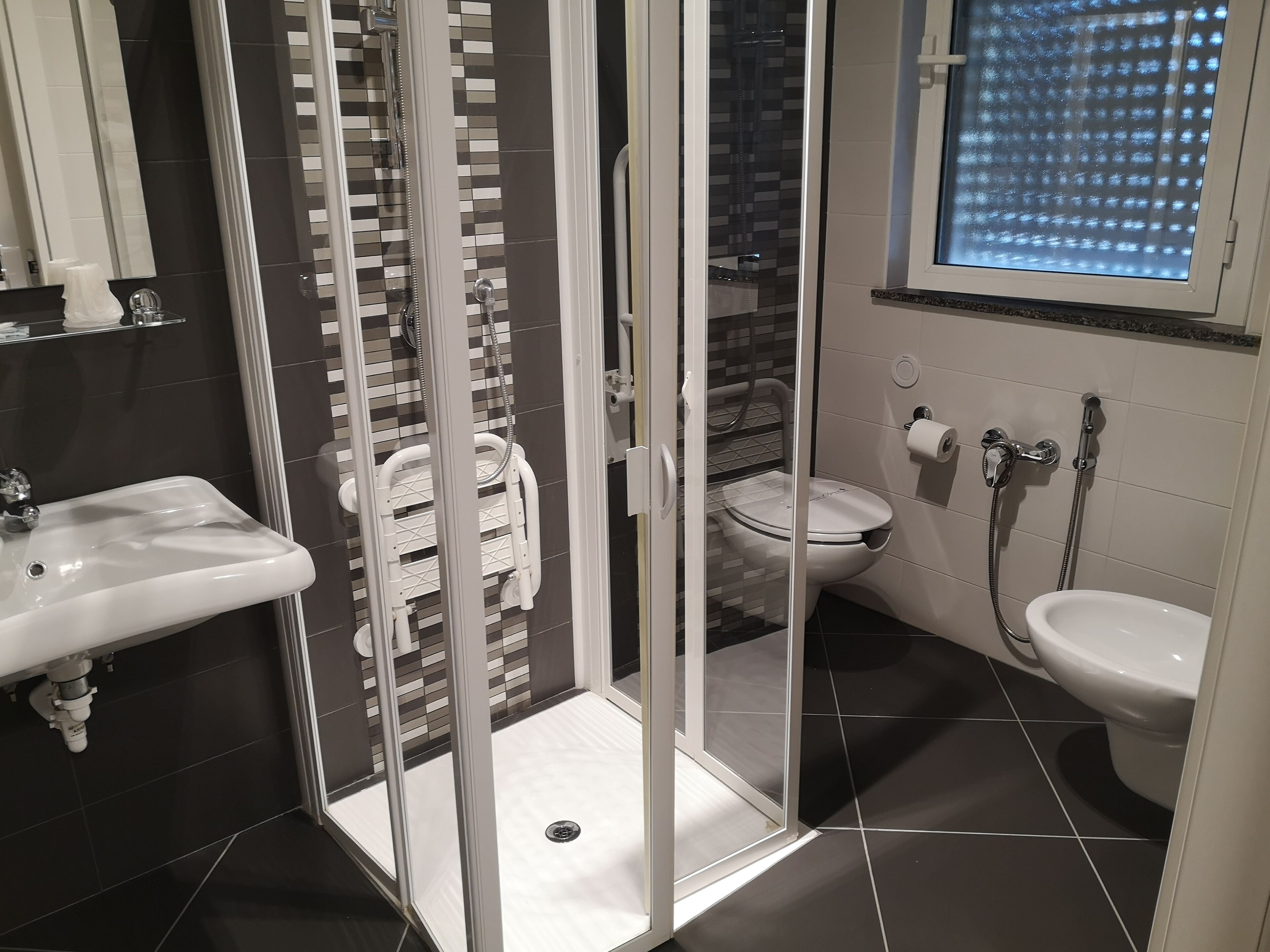 A modern bathroom with a glass-enclosed shower, a toilet, and a sink.