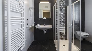Ein modernes Badezimmer mit einer Duschkabine aus Glas, einem weißen Waschbecken und einer Toilette.