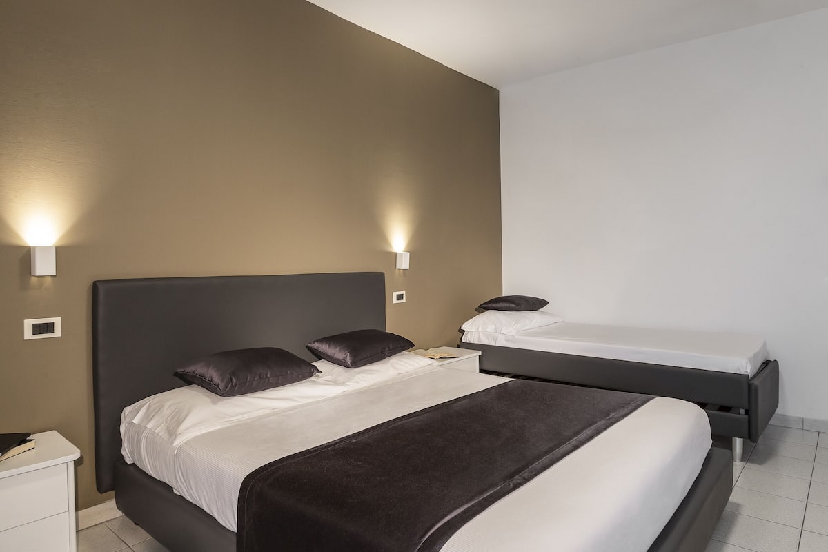 Ein Hotelzimmer mit zwei Betten, einem Nachttisch und Wandleuchten.