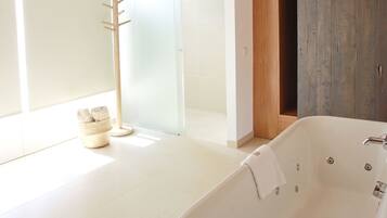 A modern bathroom with a freestanding bathtub, a wooden door, and a glass shower enclosure.