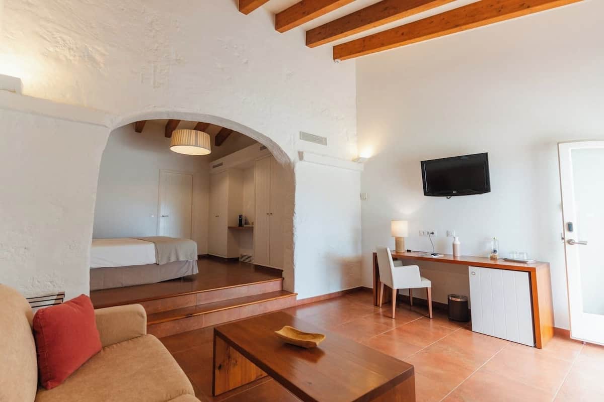 A compact living space with a sofa, a coffee table, a TV, and a kitchenette area.