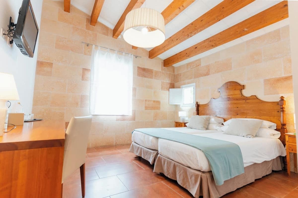 A bedroom with a wooden headboard, two beds, a desk, and a chair.