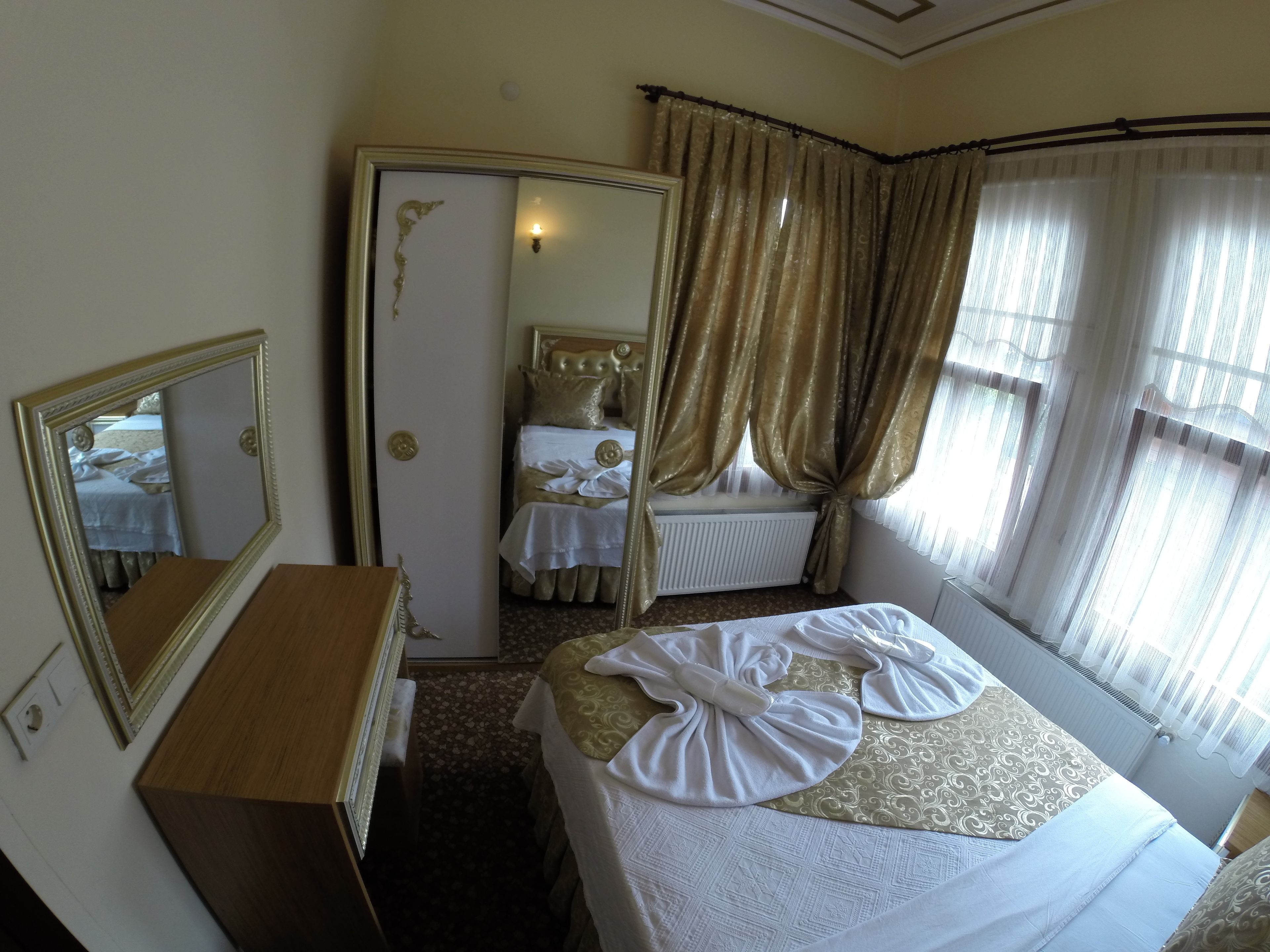 Una habitación de hotel con cama, cómoda, espejo, radiador y cortinas.