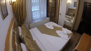 Una habitación de hotel con cama, radiador, ventana con cortinas, espejo y puerta.