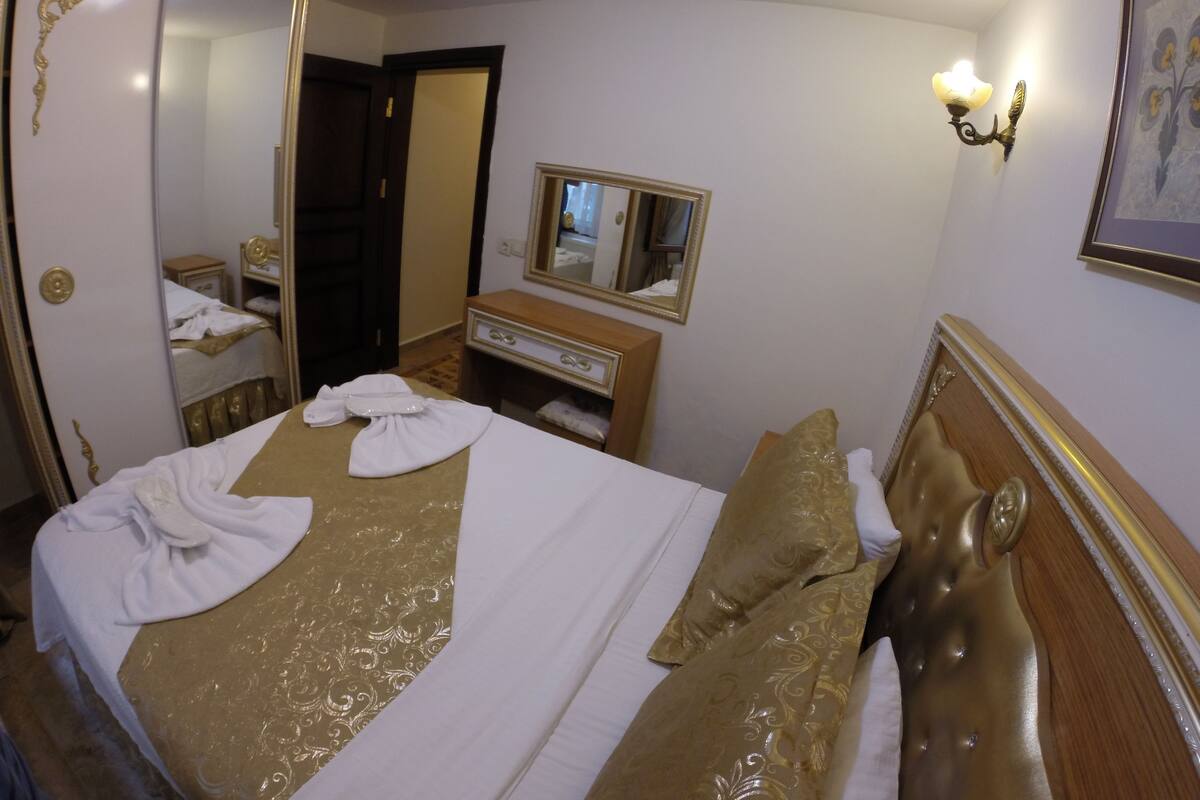 A hotel room with a large bed, a dresser, a mirror, and a wall-mounted light fixture.