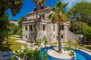 A stone building with a pool and lounge chairs.