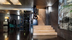 En moderne lobby med trappe, reception og et stort abstrakt maleri.