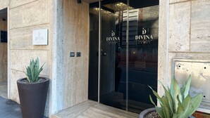 Divina luksushotellets ydre, med et moderne design, der viser en stor plantekasse og en glasklædt indgang.