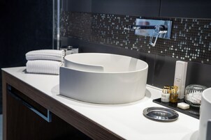 Ein modernes Badezimmer mit einem großen, weißen Waschbecken, einem Handtuch, einer Seifenspender und einem Glasbehälter.