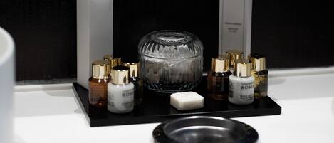 A bathroom vanity with a black tray holding various toiletries, a glass container, and a soap bar.
