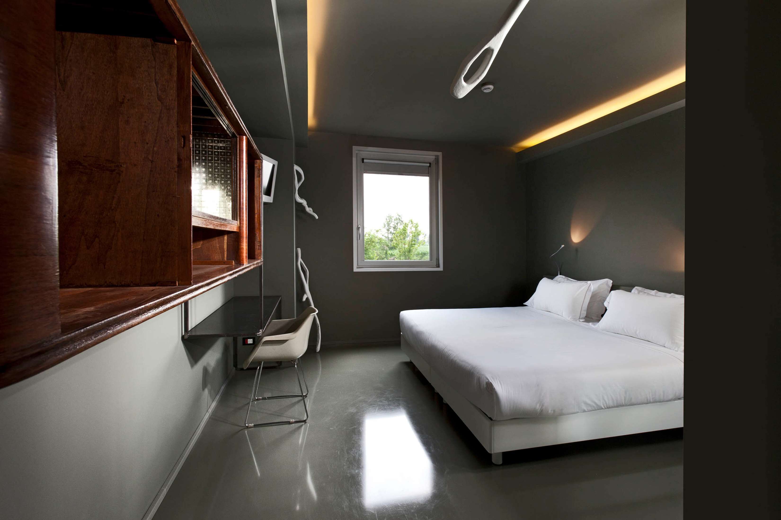 Una camera da letto moderna con un letto grande, un armadio in legno e una finestra che offre luce naturale.