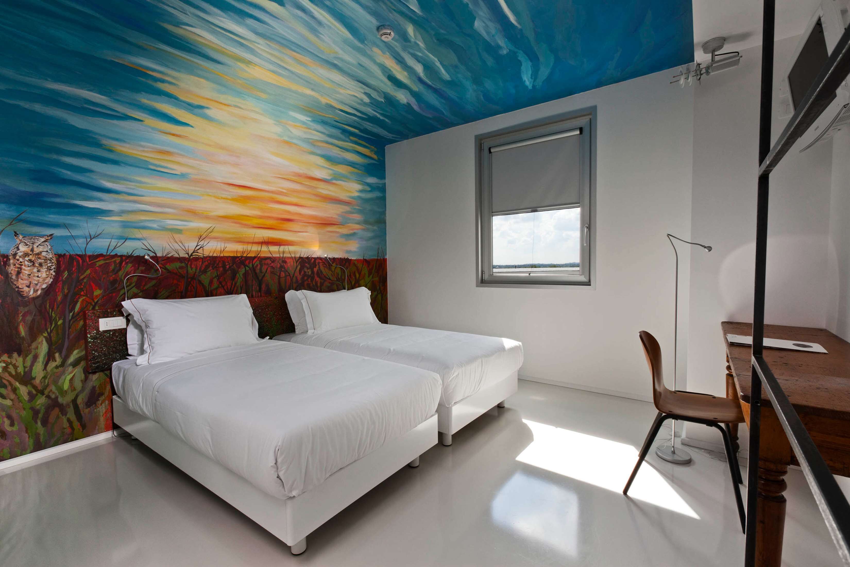 A bedroom with two beds, a desk, and a chair.