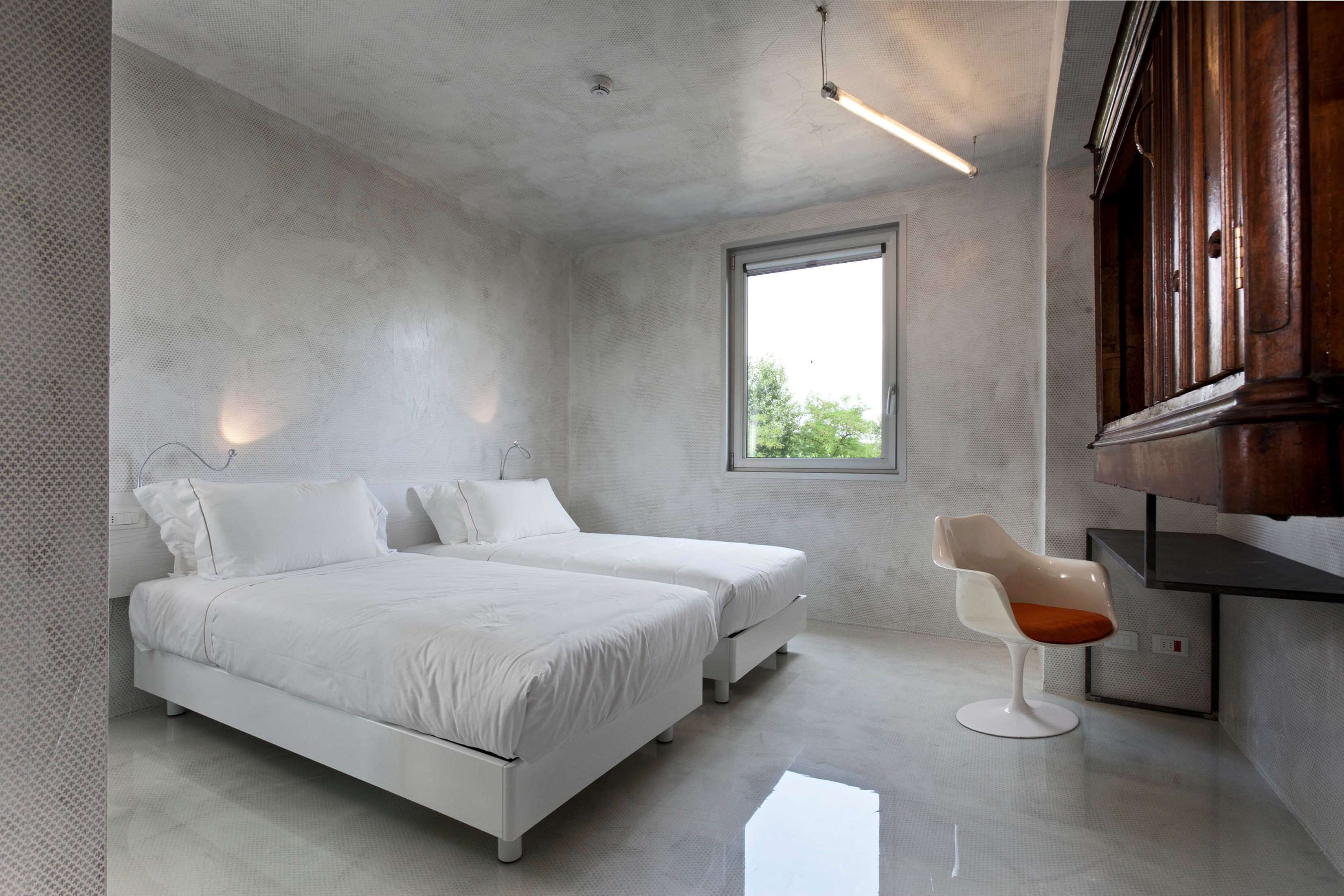 Een moderne slaapkamer met twee bedden, een raam en een houten kast.