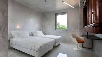 Een moderne slaapkamer met twee bedden, een raam en een houten kast.