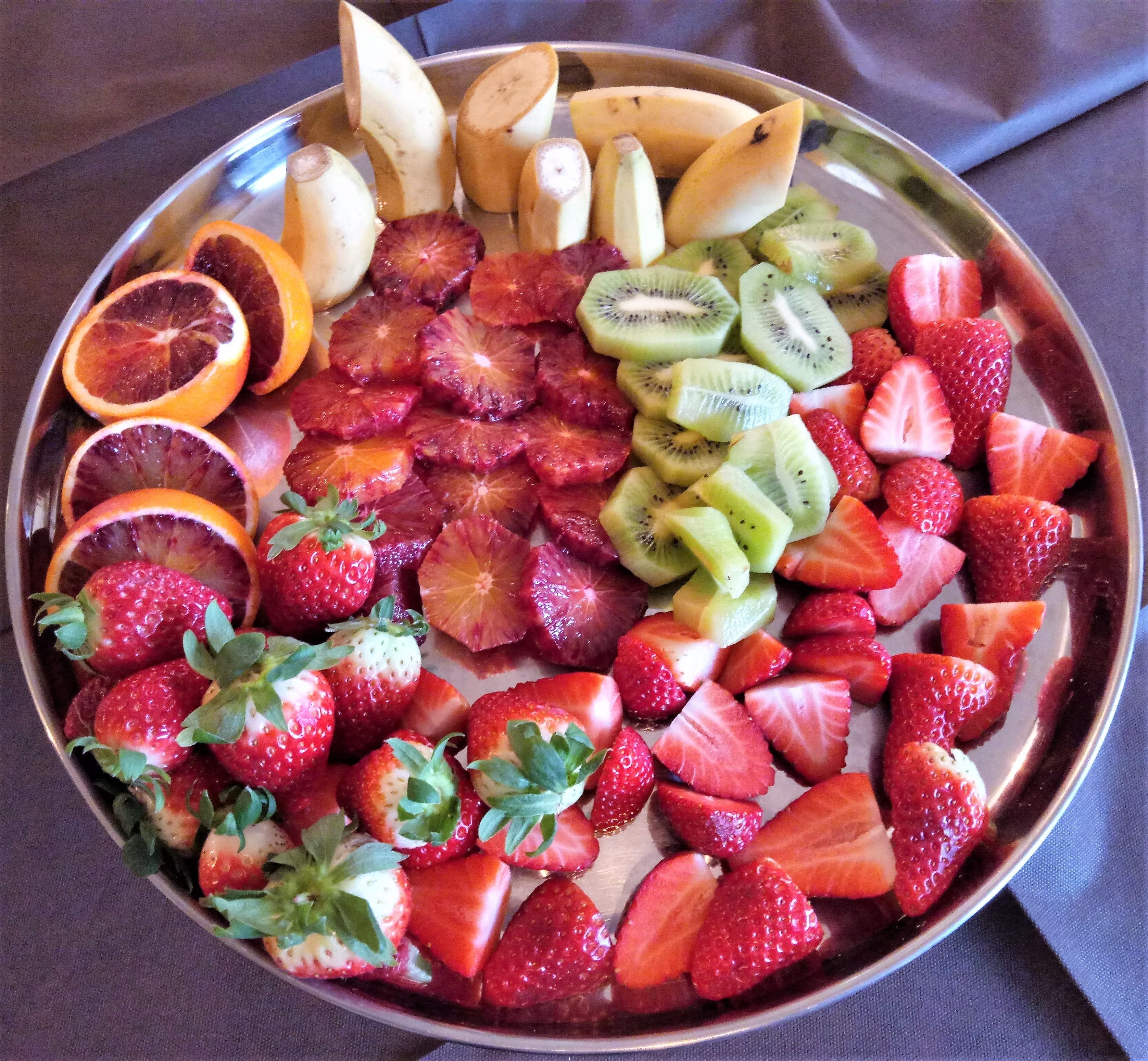 Una bandeja de frutas con fresas, kiwi, naranjas sanguinas y plátanos.