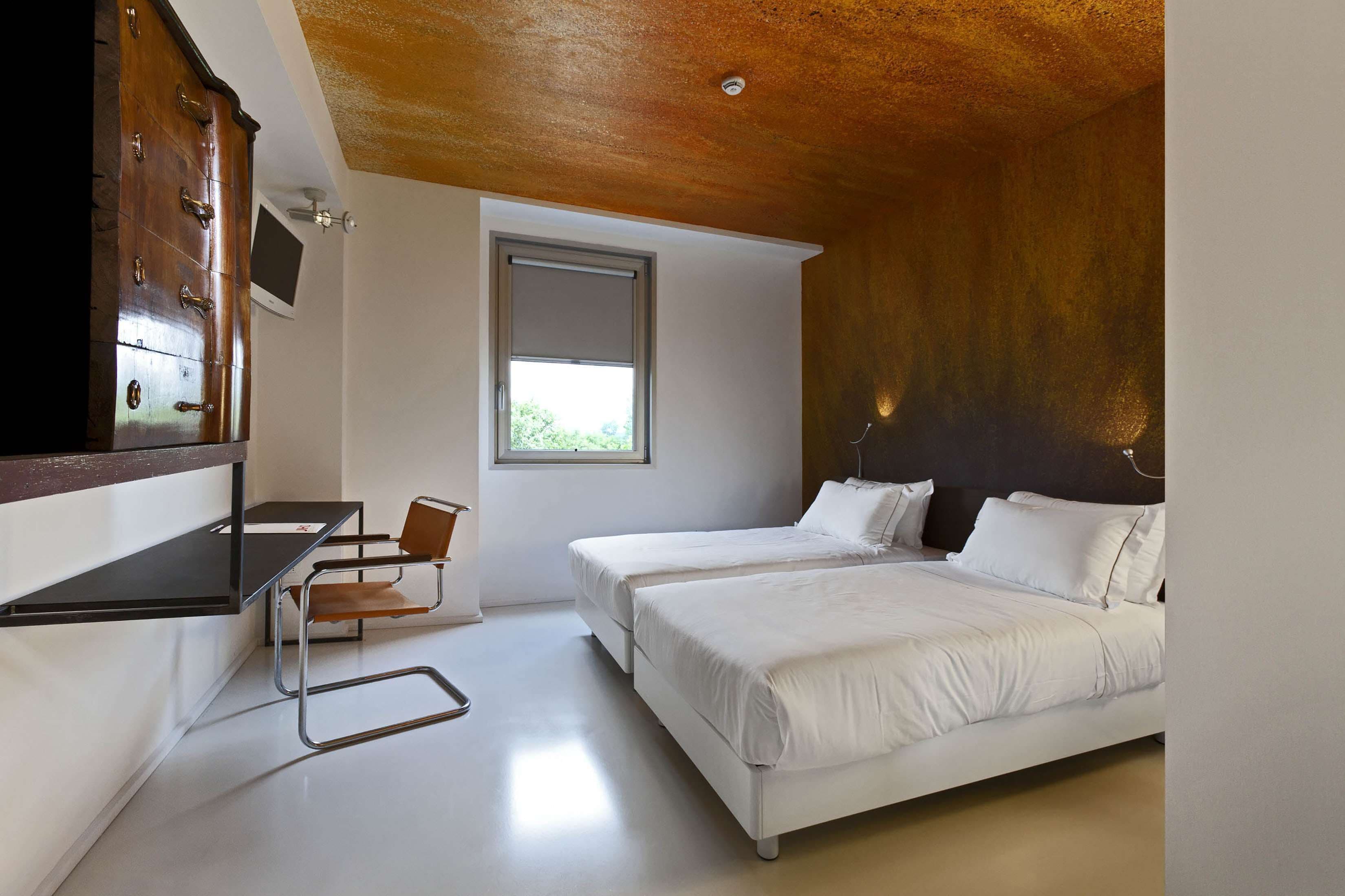 A bedroom with two beds, a desk, a chair, and a window.
