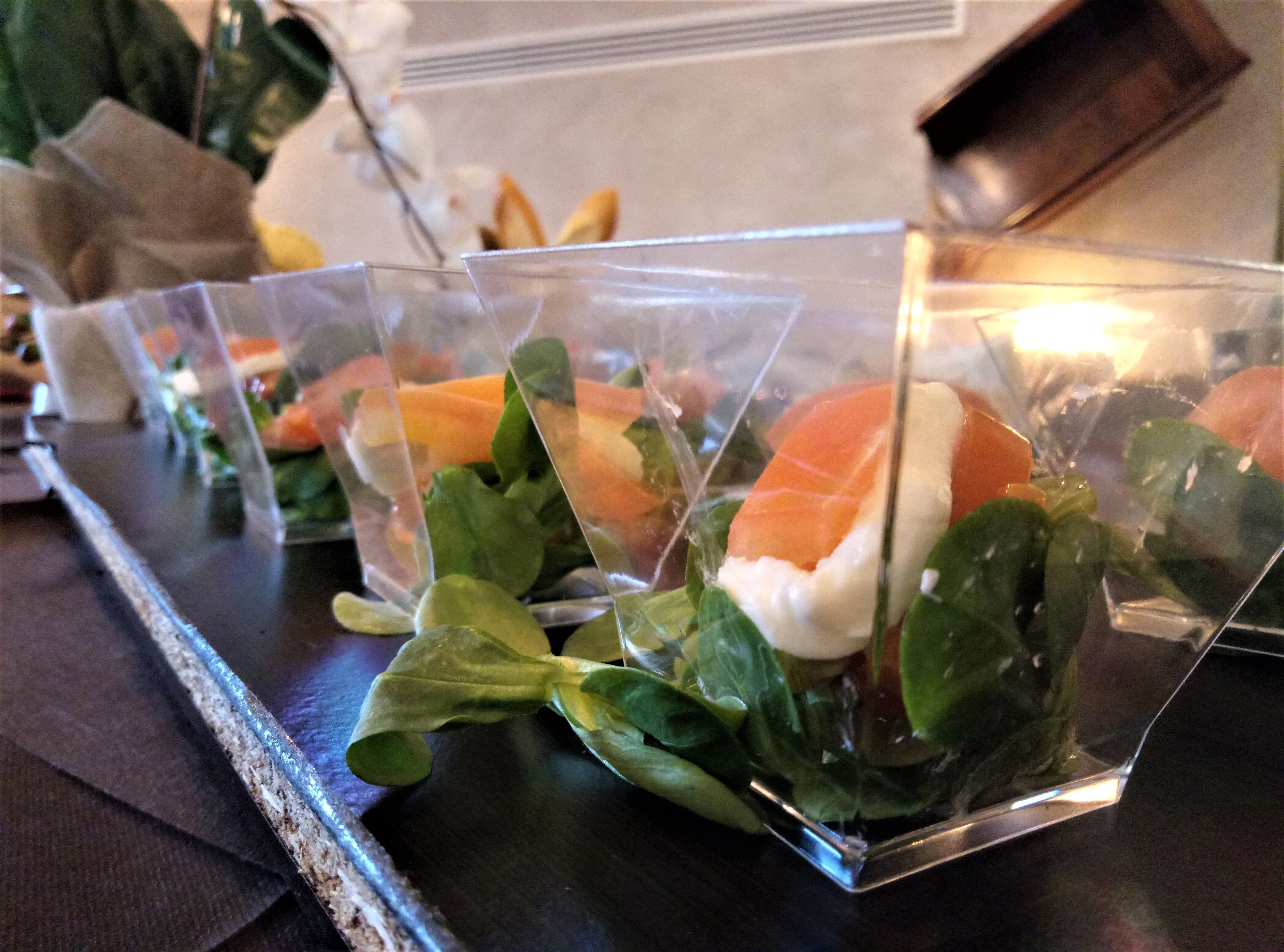 A tray of food items, including salmon and greens, on a table.