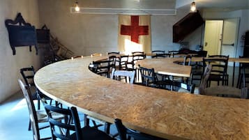 A conference room with a curved wooden table and black chairs, equipped with a ceiling light fixture and an air conditioning unit.