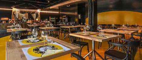 Un restaurante con varias mesas, cada una dispuesta con copas de vino y menús.