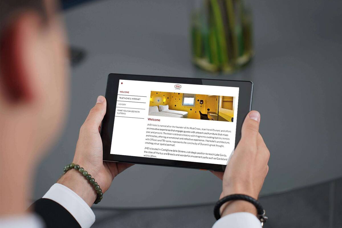 Une tablette affiche l’intérieur d’un hôtel au design moderne, avec un lit, un bureau et une chaise.
