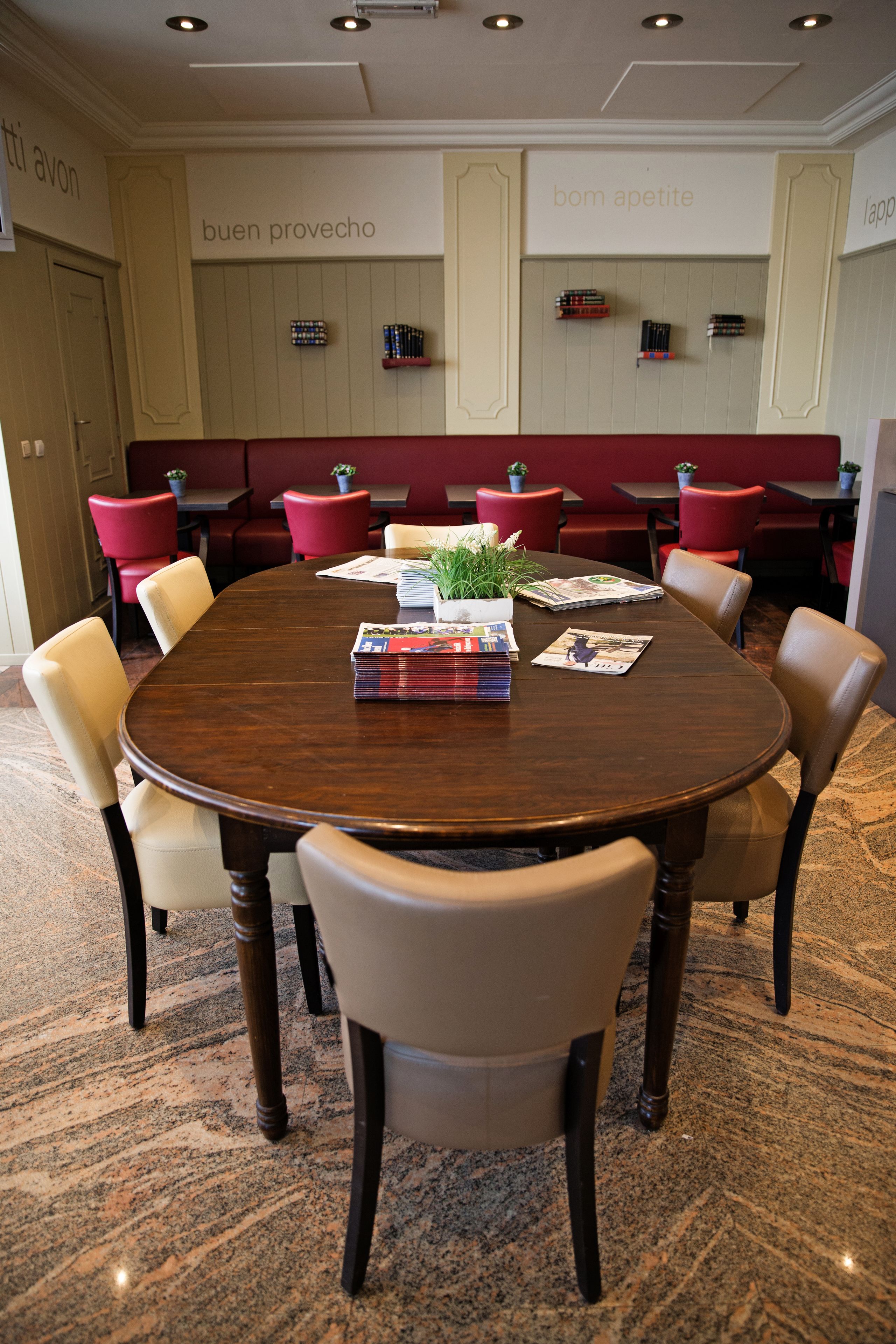 Un salón de conferencias con una mesa redonda, sillas color beige y asientos tapizados en rojo.