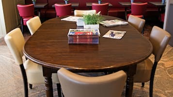 Un salón de conferencias con una mesa redonda, sillas color beige y asientos tapizados en rojo.