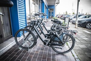 Uma bicicleta estacionada em um passeio de azulejos em frente a um edifício com detalhes em azul e branco.