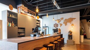 A bar area with stools, a counter, and a world map on the wall. - Antwerp Harbour Hotel (Antwerp)
