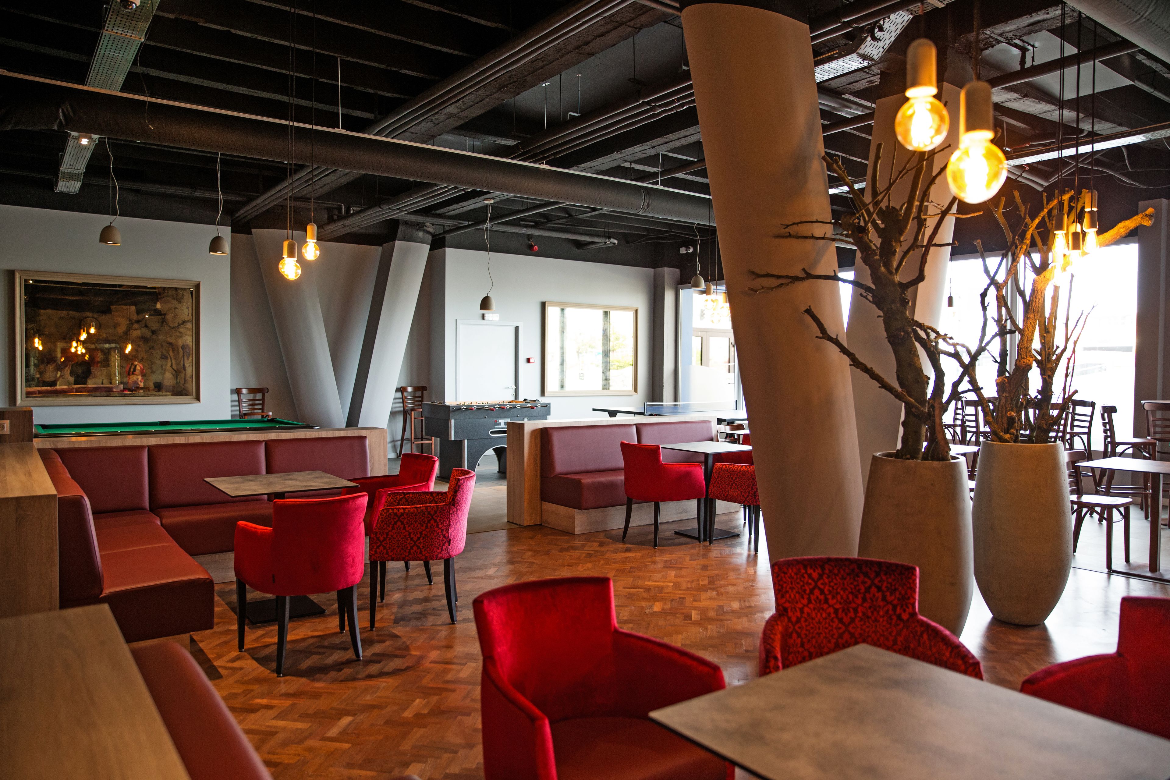 Un restaurant avec des sièges rouges, une table de billard et de grandes fenêtres.