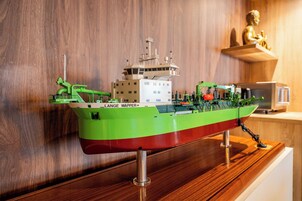 Un modelo de barco con el nombre 'LANGE WAPPER' en el costado, exhibido sobre un soporte de madera.