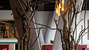 Two large concrete vases with branches, a modern light fixture, and red chairs in a contemporary interior space. - Antwerp Harbour Hotel (Antwerp)