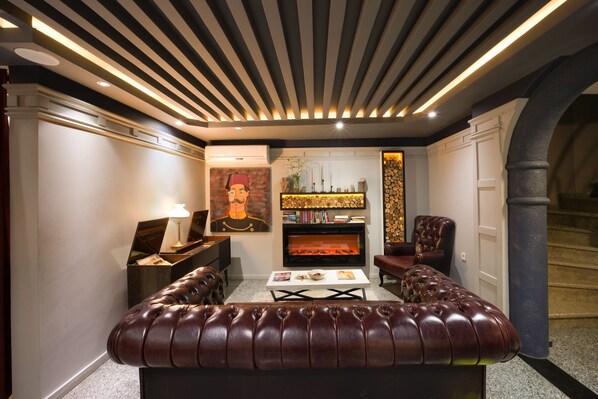 Uma sala de estar moderna com lareira, sofá de couro e um piano.