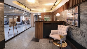 A modern lobby with a marble reception desk, a plush armchair, and a glass wall leading to a dining area. - Harbiye Residence (Istanbul)