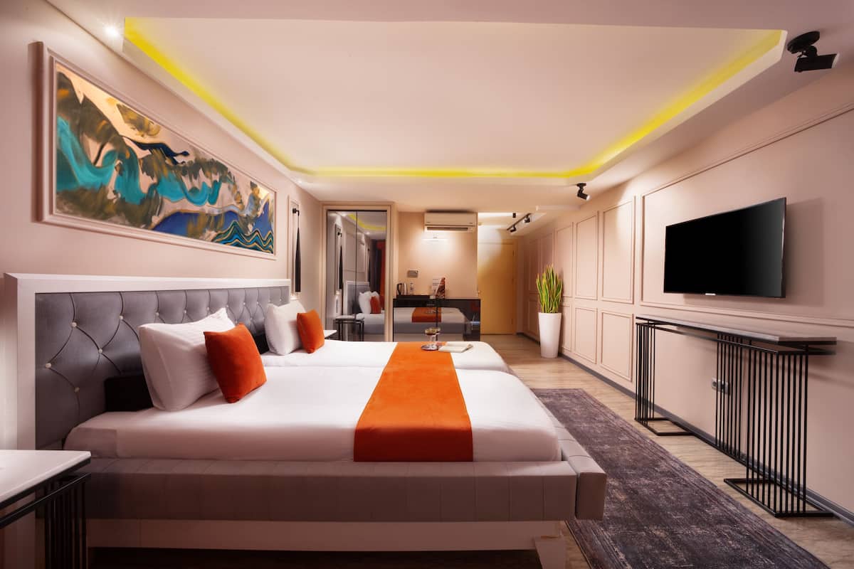 A modern hotel room with a large bed, a flat-screen TV, and a painting on the wall.