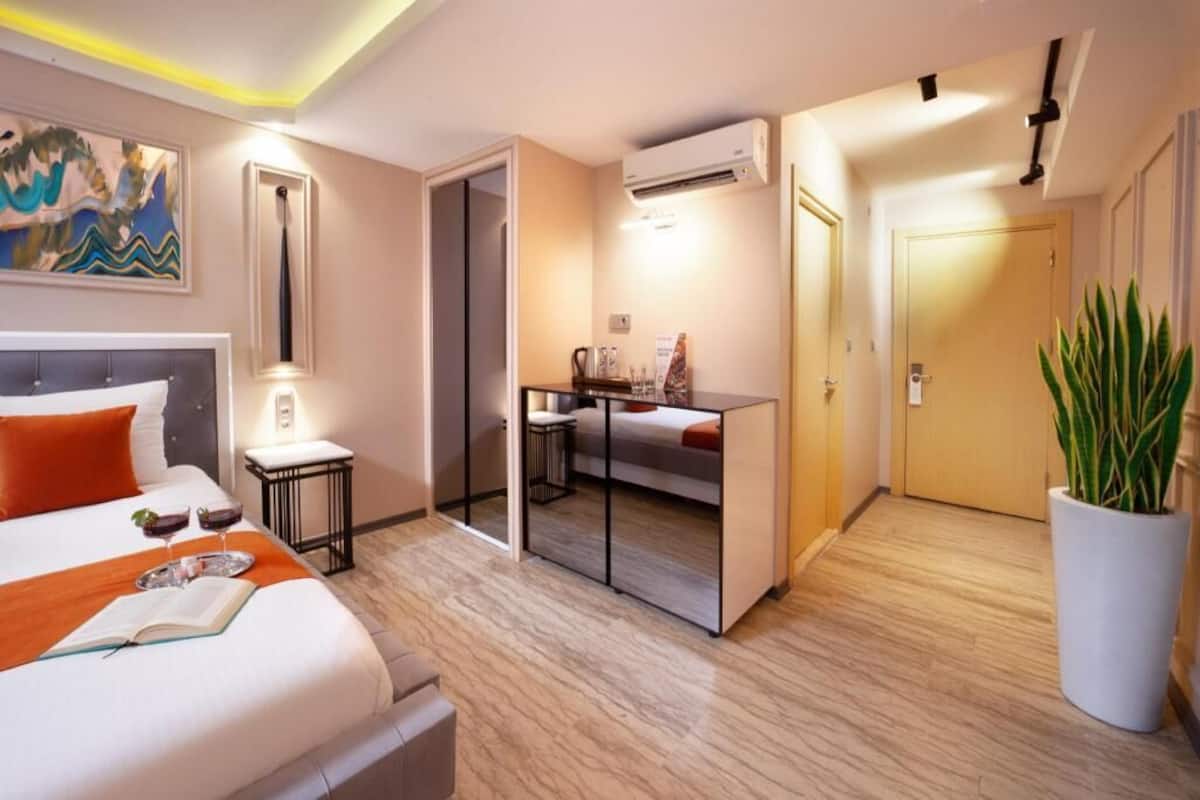 A hotel room with a bed, desk, and potted plant.