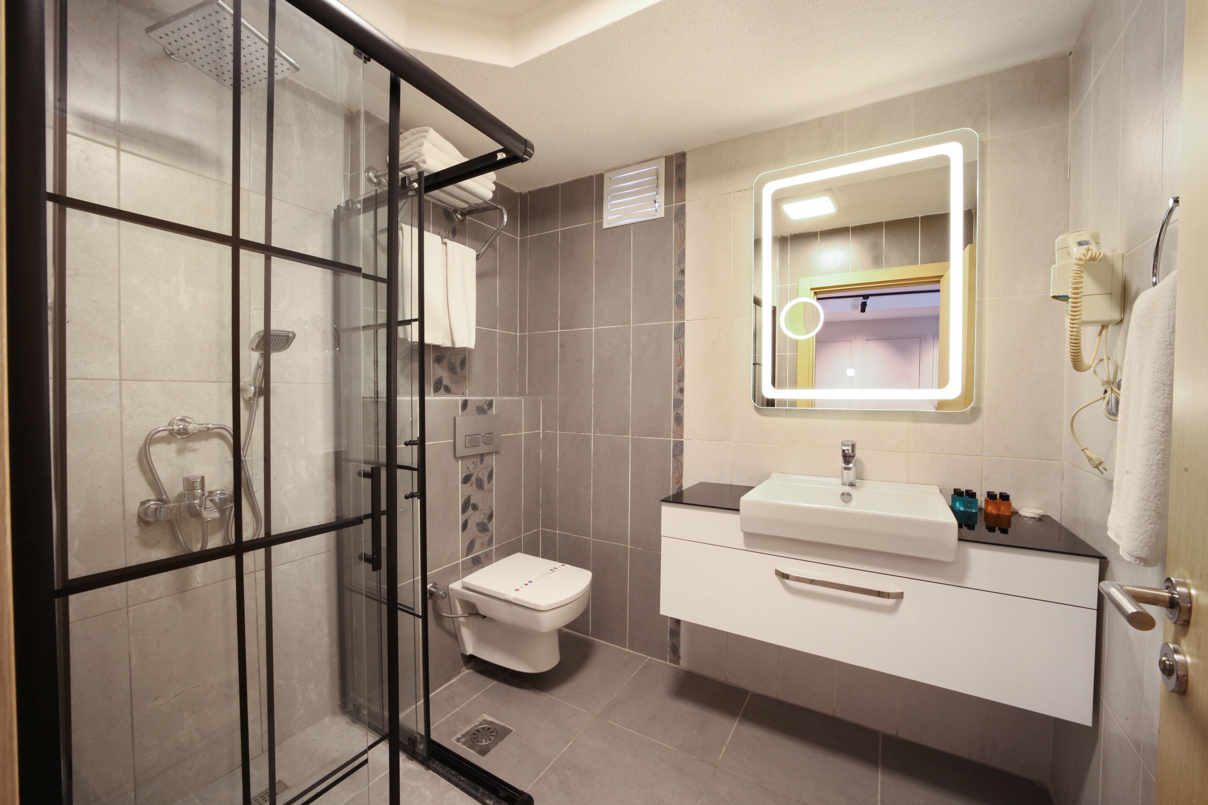 A modern bathroom with a glass shower enclosure, a toilet, a sink with a mirror, and a towel rack.