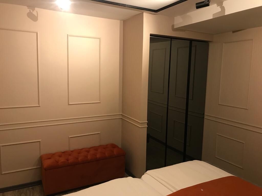 Een slaapkamer met een bed, een bankje en een schuifdeurkast.