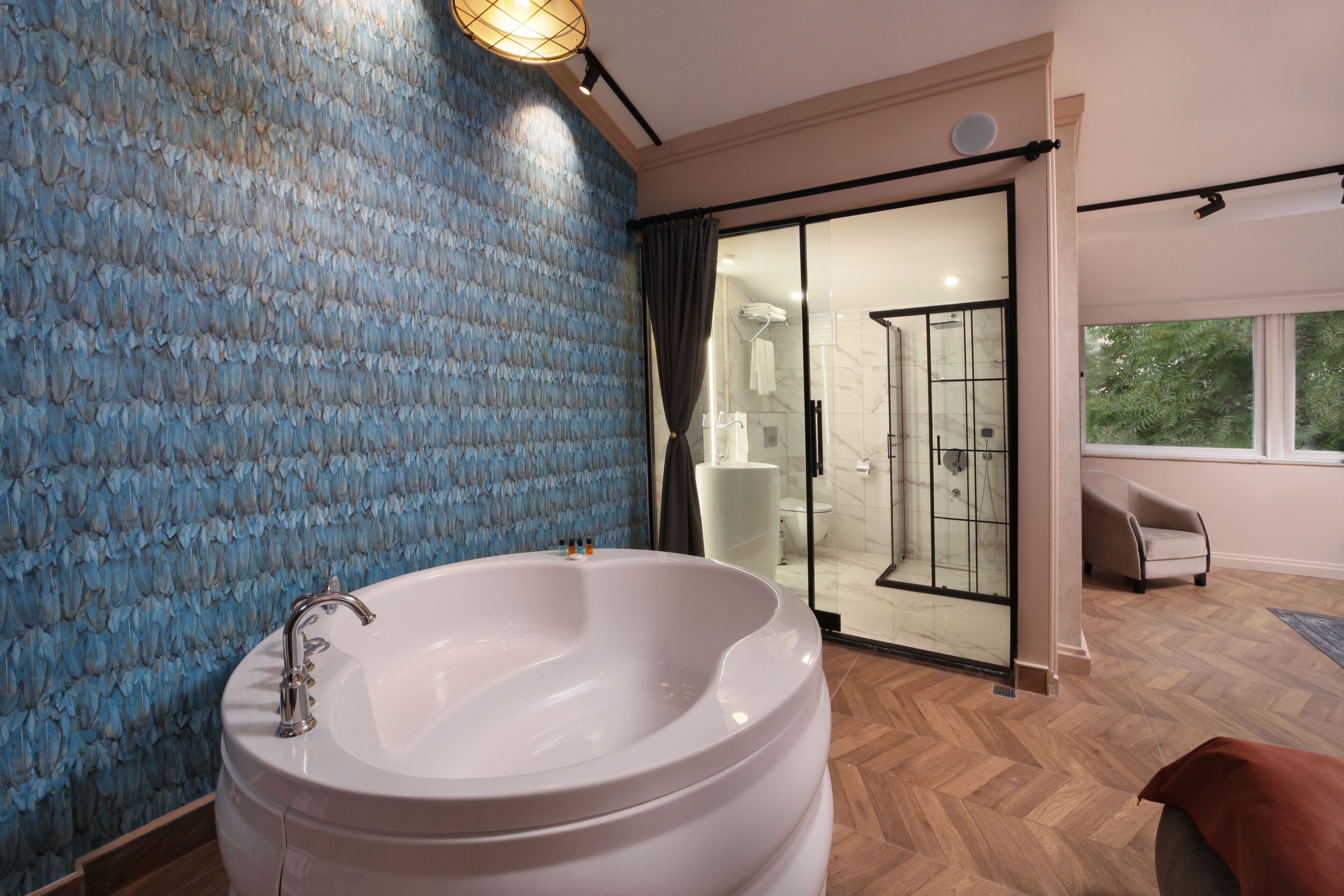 A modern bathroom with a large bathtub, a glass shower enclosure, and a view of the outdoors.