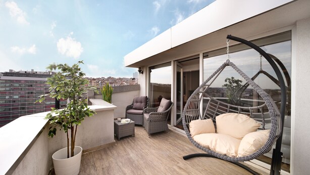 A rooftop terrace with a hanging chair, two cushioned chairs, a potted plant, and a view of the cityscape. - Harbiye Residence (Istanbul)