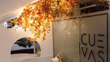A bathroom with a large bathtub, a glass shower enclosure, and a decorative leaf arrangement.