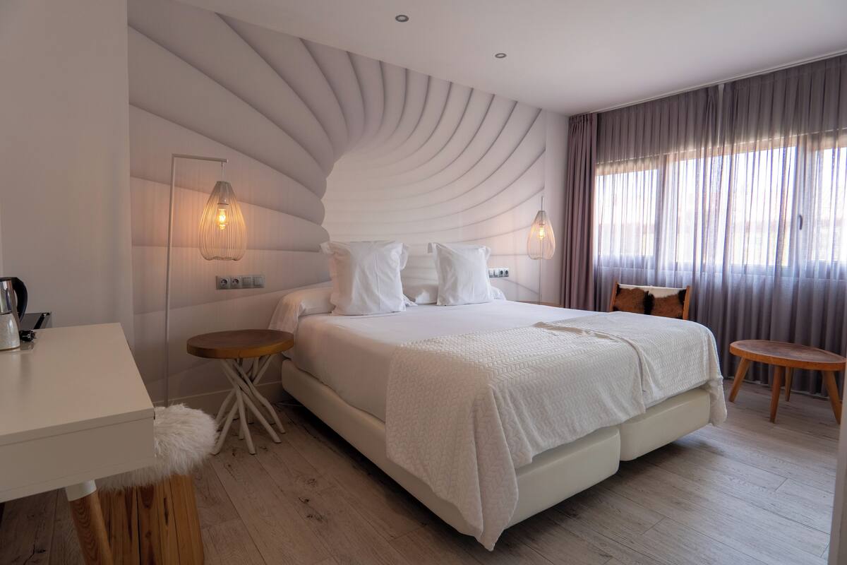 Un dormitorio moderno con una cama grande, mesitas de noche y un escritorio.