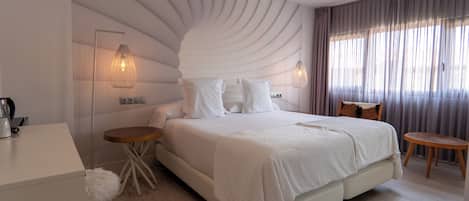 A modern bedroom with a large bed, bedside tables, and a desk.