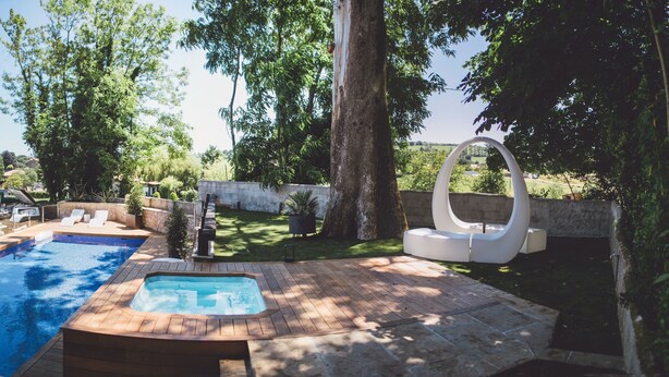 Een zwembadgedeelte met een jacuzzi, ligbedden en een terras van natuursteen.