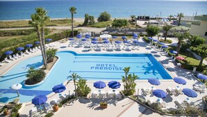 A hotel pool area with lounge chairs and umbrellas, a clear view of the ocean, and the text "HOTEL PARADISE" on the pool. - Hotel Village Paradise (Mandatoriccio)